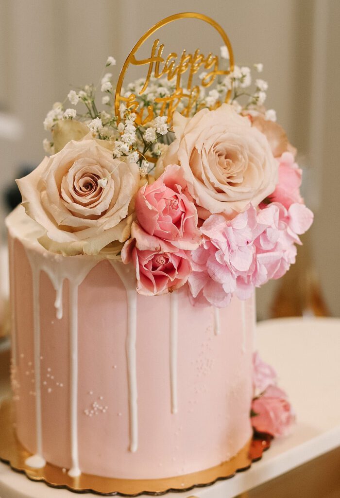 Pink blush drip cake adorned with pink flowers and bays breath